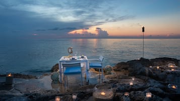 A table set for two with a view of the sea at sunset.