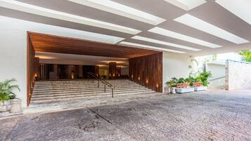 A modern building entrance with a wooden facade, stone steps, and potted plants.
