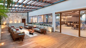 Un espace de détente moderne doté d’un plancher en bois, d’un mur en pierre et d’un coin salon avec des canapés et des tables.