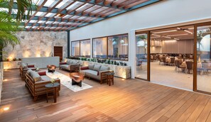 A modern lounge area with wooden flooring, a stone wall, and a seating area with sofas and tables. - InterContinental Presidente Cozumel Resort Spa by IHG (Cozumel)