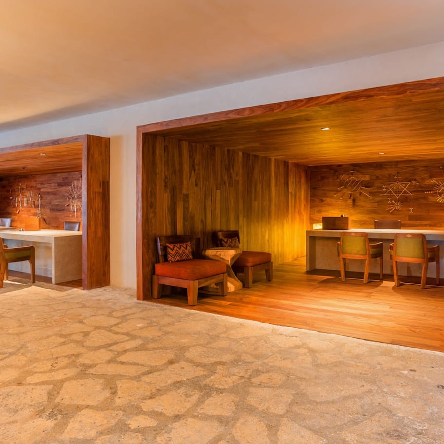 A modern hotel lobby with a stone floor, wooden reception desk, and seating area.