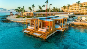 Des bungalows sur pilotis, avec une eau cristalline, une terrasse en bois et des chaises longues.