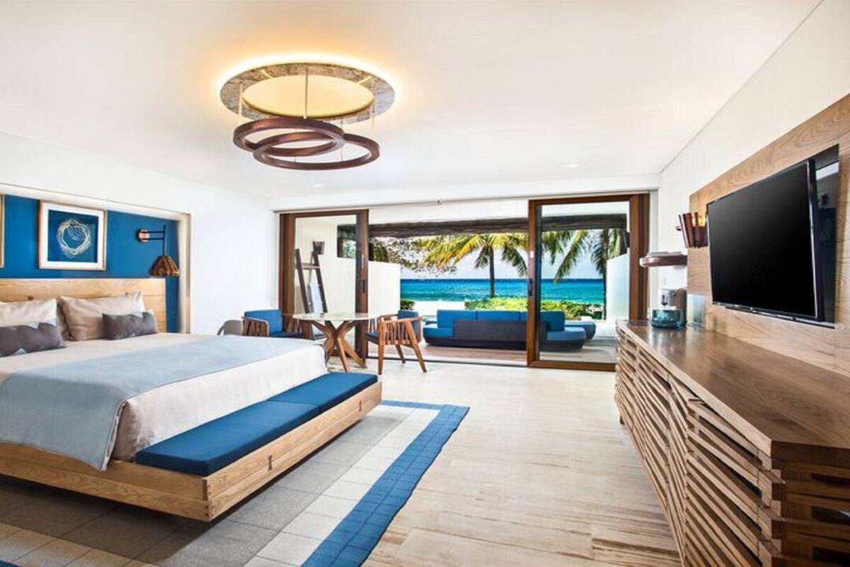 Une chambre moderne avec un grand lit, une télévision et une vue sur l’océan.