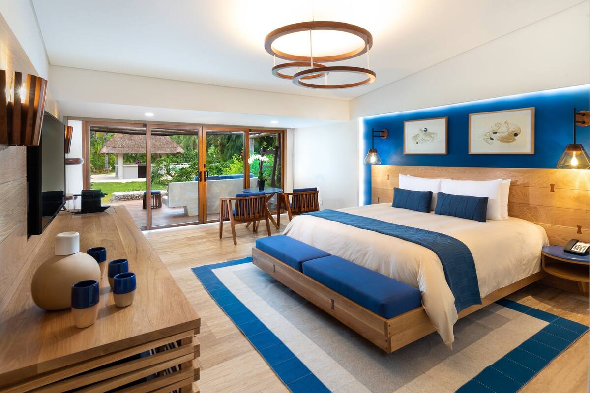 Une chambre moderne avec un grand lit, un bureau en bois et un coin repas comprenant une table et des chaises.