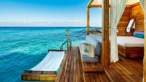 A wooden deck with a white towel, a bag, and a bed with a blue pillow. - InterContinental Presidente Cozumel Resort Spa by IHG (Cozumel)