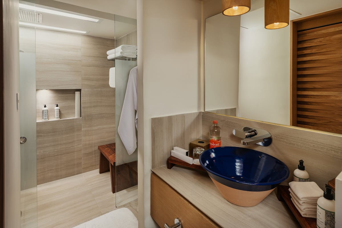 Une salle de bain moderne avec un grand lavabo bleu, un meuble-lavabo en bois et un miroir.