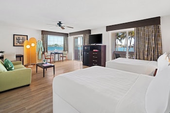 A living room with a green sofa, a coffee table, a TV, and a dining area with chairs and a table. at Palm Tree Club Miami Hotel