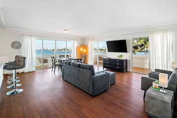 A hotel room with a bed, a sofa, a desk, a TV, and a balcony with a view of the sea. at Palm Tree Club Miami Hotel