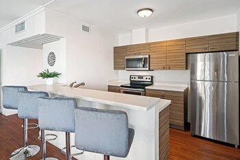 A hotel reception area with a desk, computers, and four white chairs. at Palm Tree Club Miami Hotel