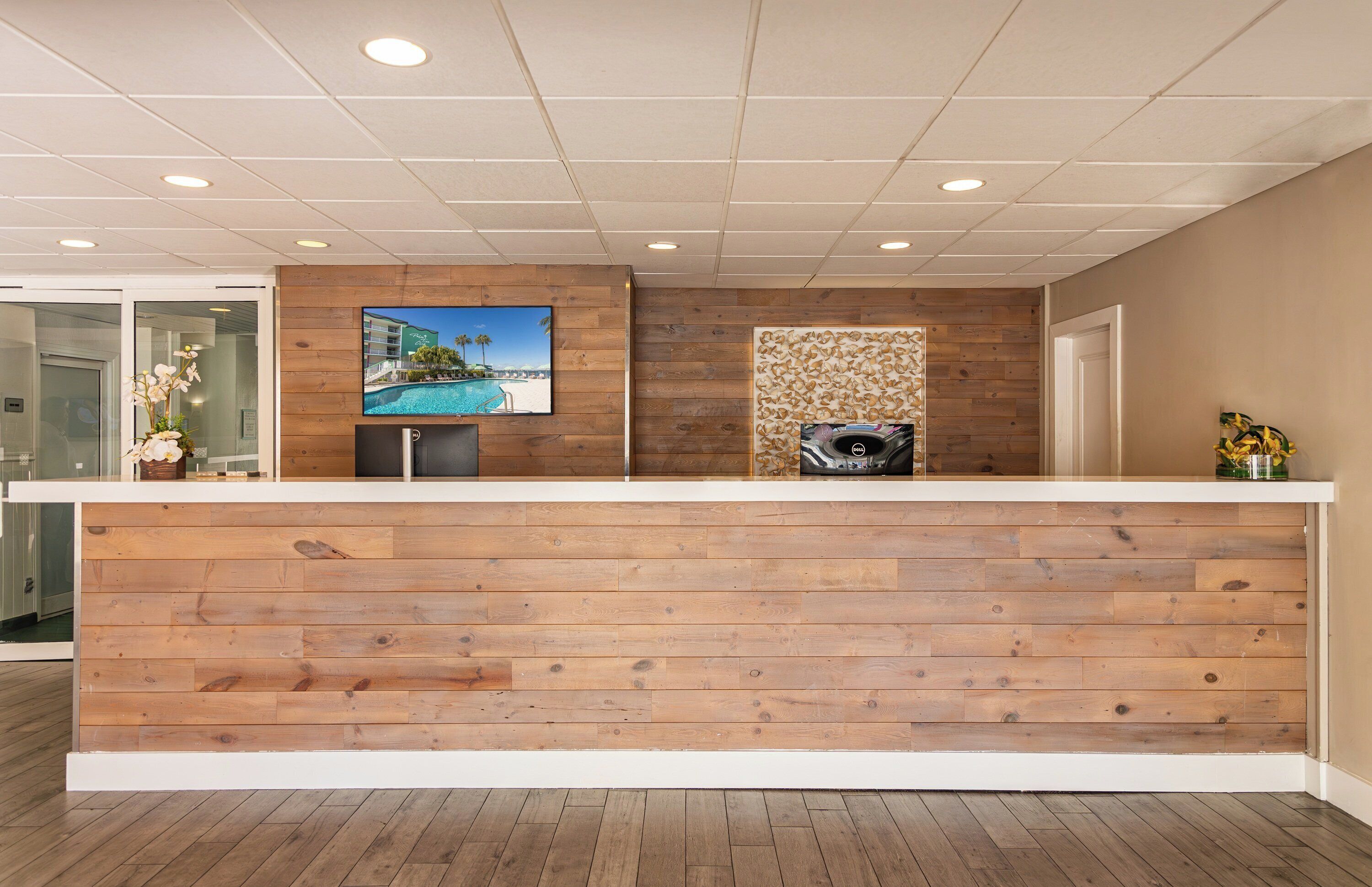 A reception desk with a wooden finish, a flat-screen TV, and a decorative wall panel.