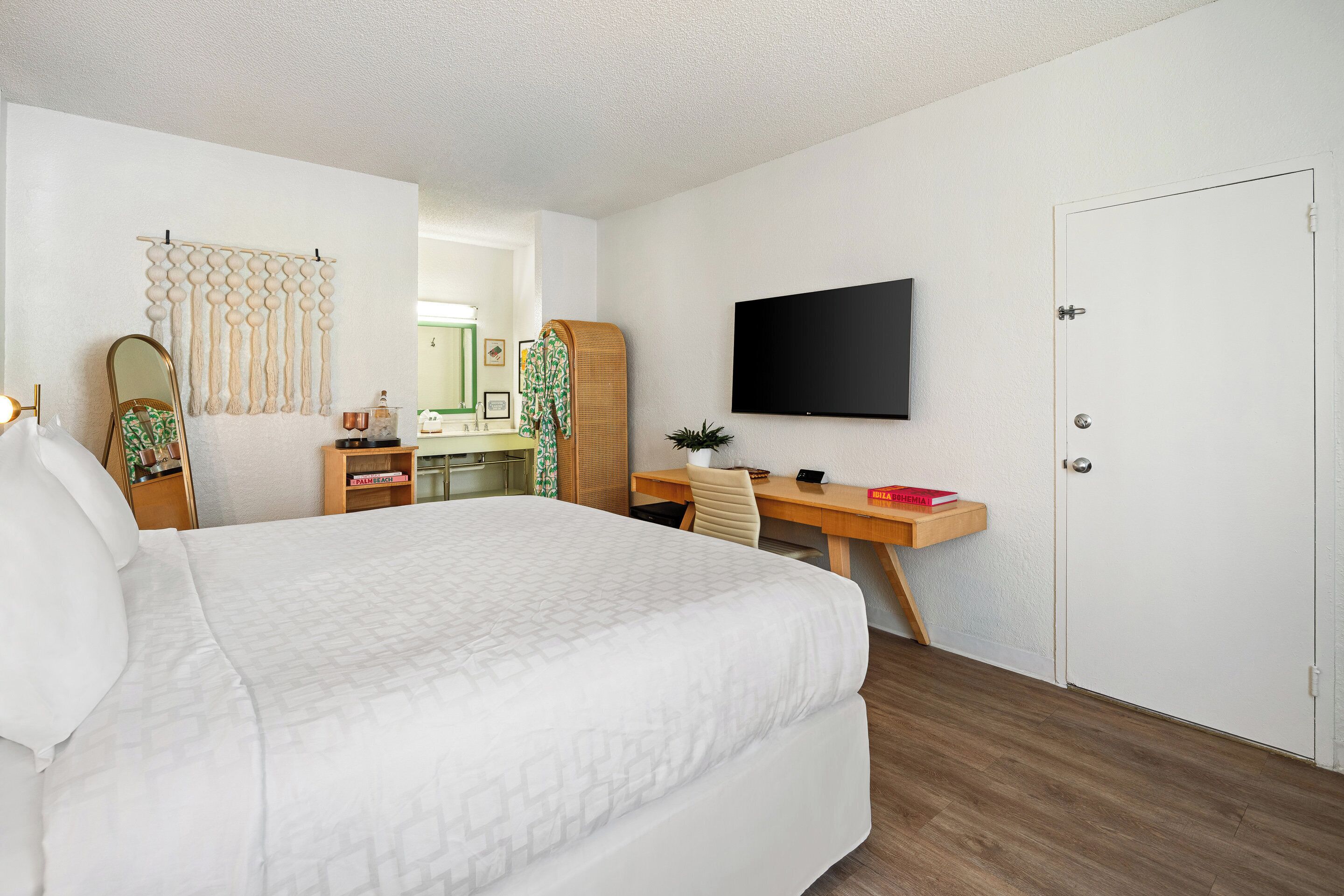 Habitación de hotel con cama, escritorio, silla, televisor y armario.