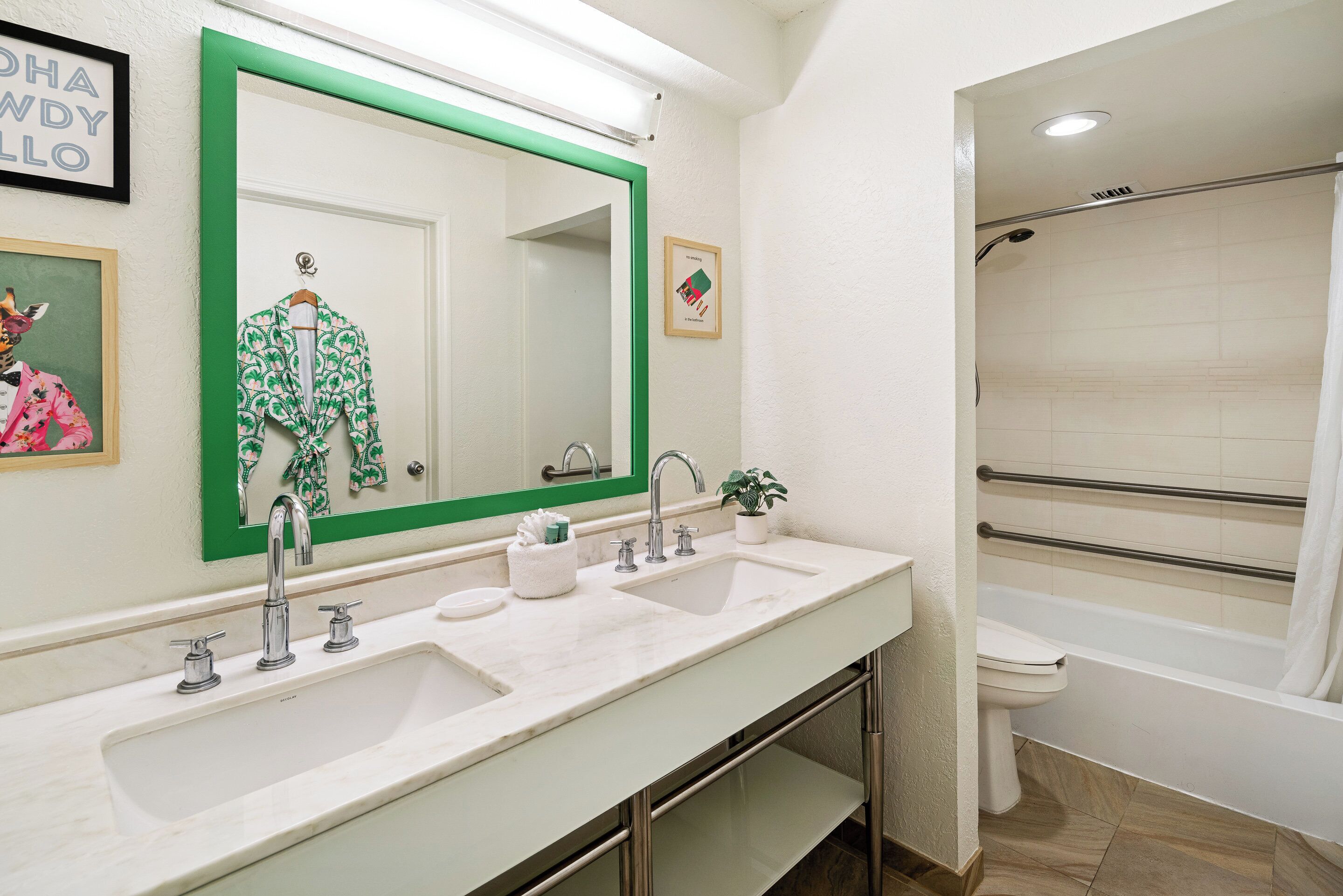 Een badkamer met een witte wastafel, een spiegel met groene lijst, een toilet en een douchehoek.