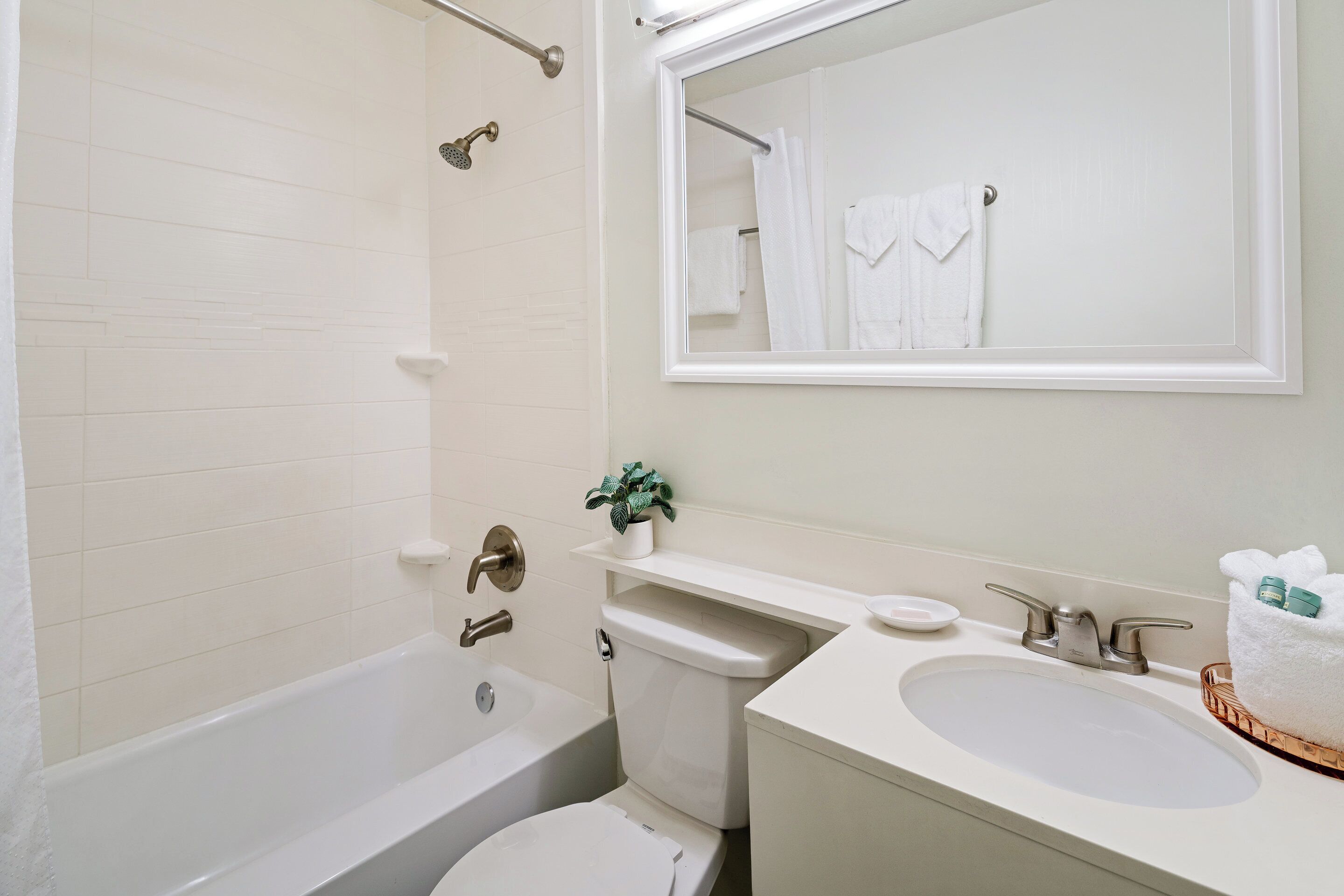 A bathroom with a bathtub, toilet, sink, and a mirror.