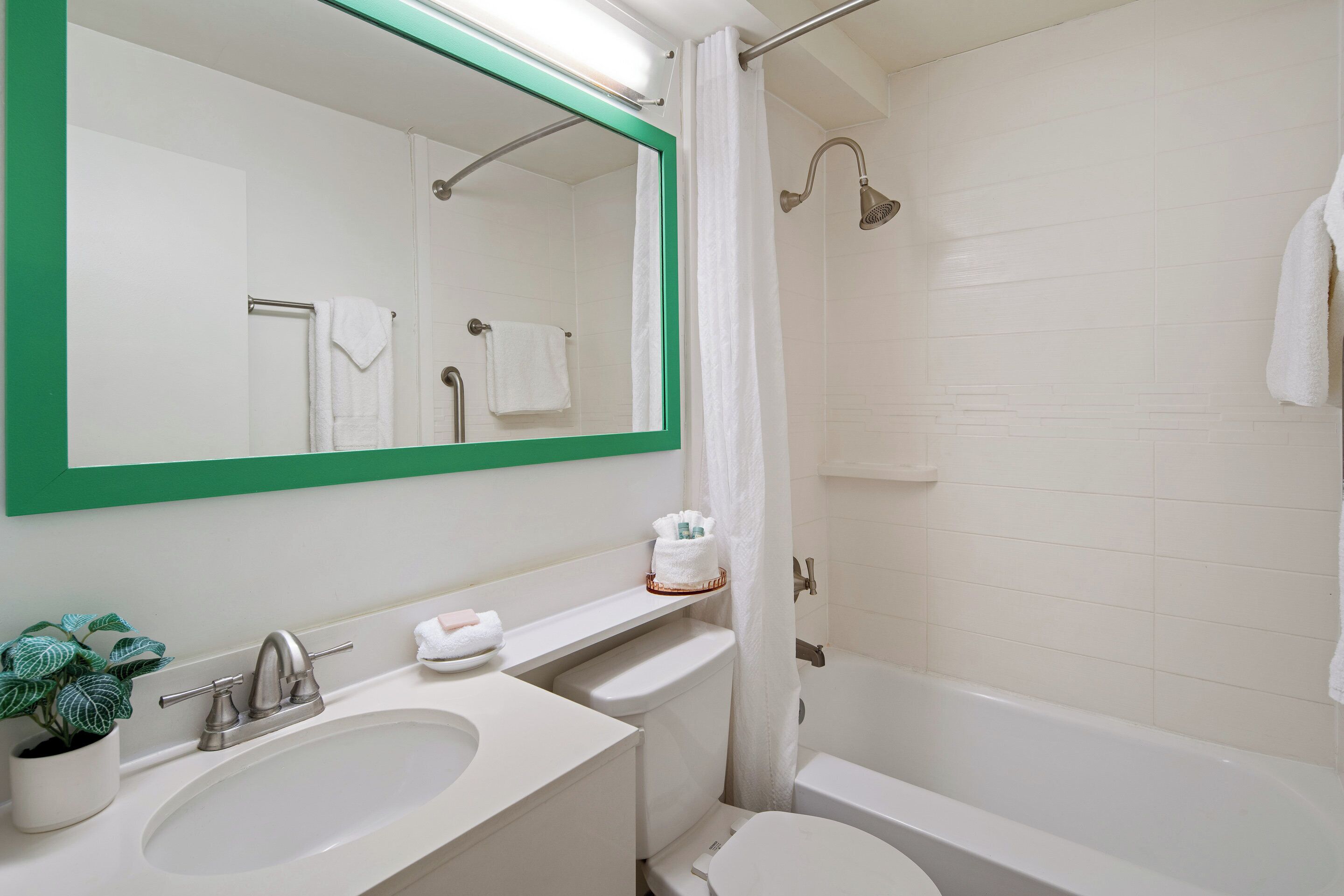 Une salle de bain équipée d’un lavabo, d’un miroir, d’une douche et de toilettes.