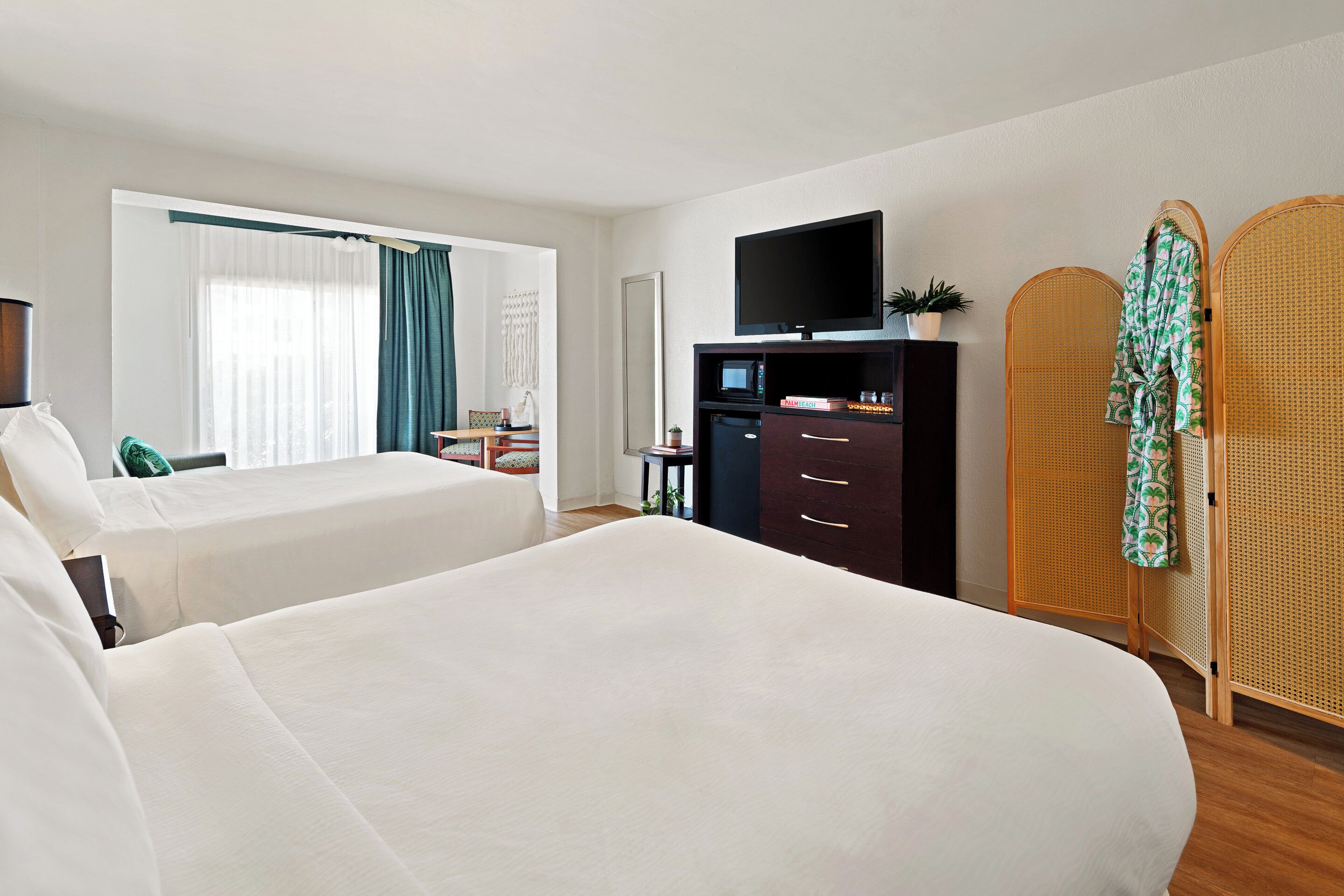 A hotel room with two beds, a TV, a desk, and a wardrobe.