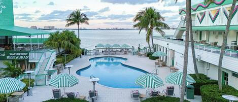 A resort with a swimming pool, outdoor seating, and a waterfront view.