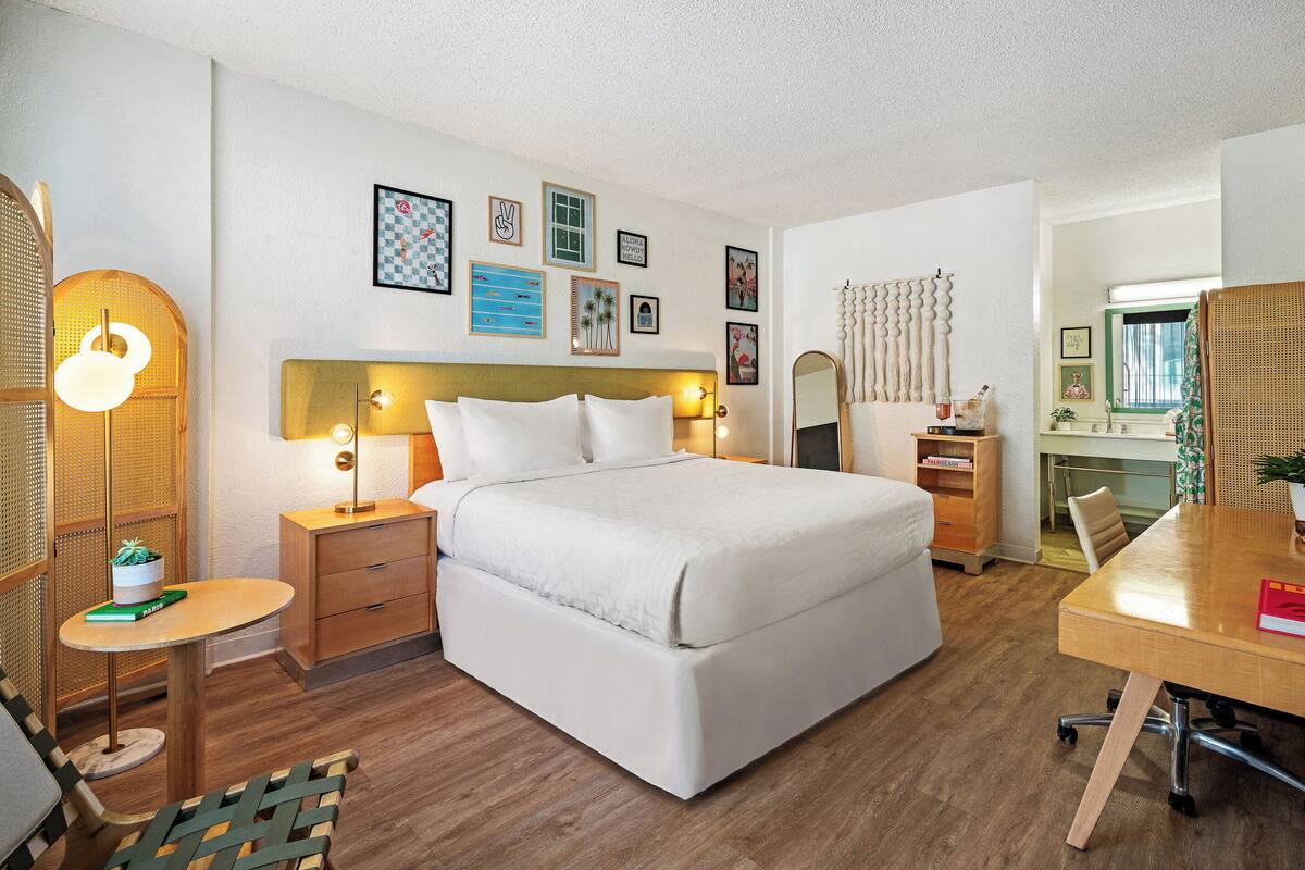 A modern hotel room with a large bed, bedside tables, a desk, and a chair.