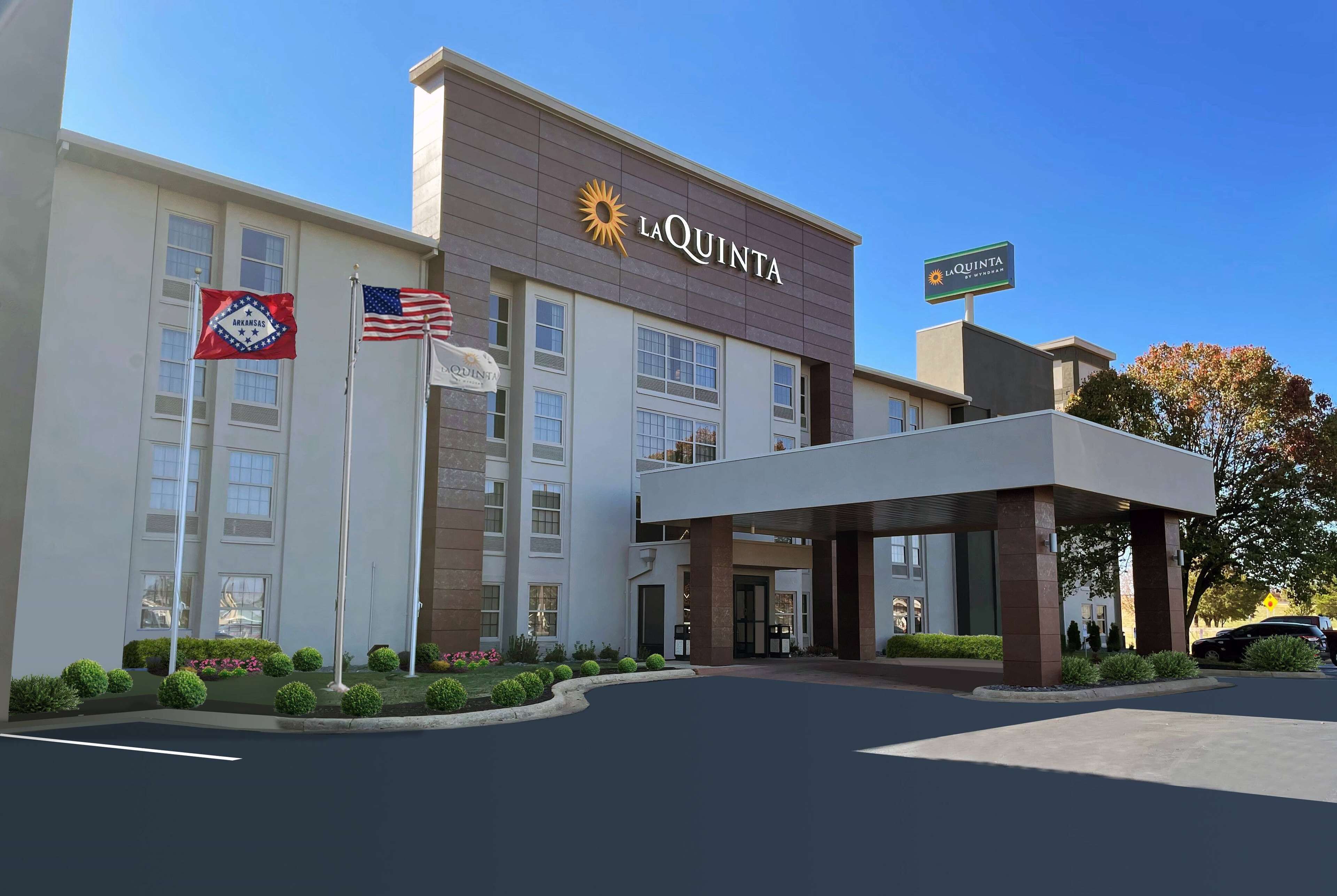 A hotel with a modern facade, a prominent 'La Quinta' sign, and a flagpole with the American flag.