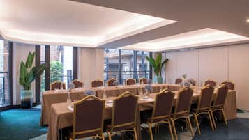 Une salle de conférence avec une longue table, des chaises et de grandes fenêtres.