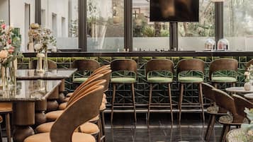 Interior de un restaurante con barra, mesas y una pantalla de televisión.