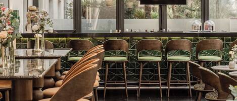A restaurant interior with a bar area, seating arrangements, and a television screen.