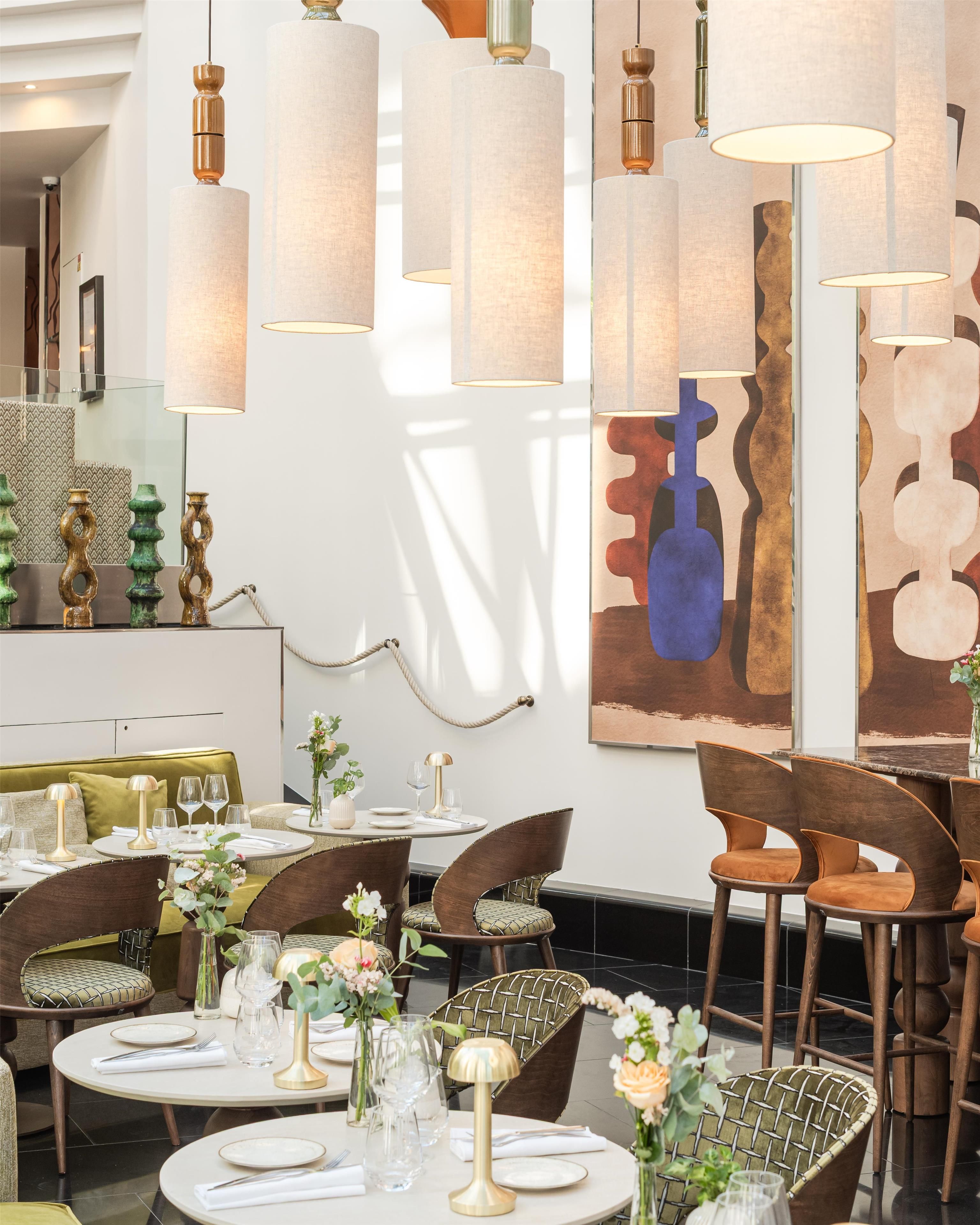 A dining area with round tables, chairs, and hanging pendant lights.