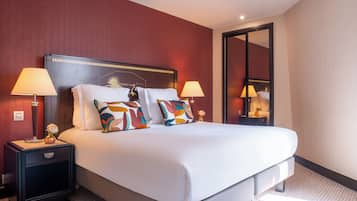 A hotel room with a large bed, two bedside tables with lamps, and a mirror on the wall.