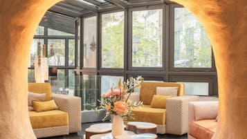 A modern interior with a unique arch structure, seating arrangements, and a central table with a vase of flowers.