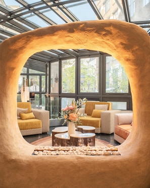 Un interior moderno con una estructura de arco distintiva, arreglos de asientos y una mesa central con un florero.