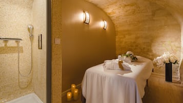 Une salle de bain avec douche, un lit avec des serviettes, des bougies et un vase rempli de fleurs.