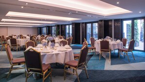Un salón de banquetes con mesas redondas, sillas y una alfombra azul.