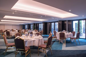 Una sala da banchetti con tavoli rotondi, sedie e un tappeto blu.