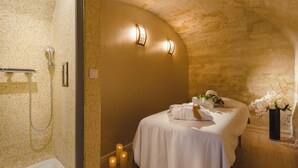 Un baño con bañera, ducha con puerta de cristal, cama con toallas y un florero con flores.
