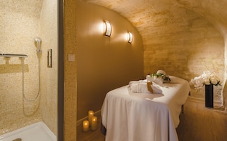 Un bagno con una vasca, una doccia con porta in vetro, un letto con asciugamani e un vaso di fiori.