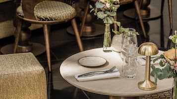 A dining area with round tables, chairs, and neatly set tables with plates, cutlery, and glassware.