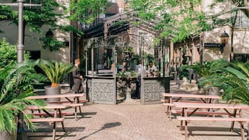 Un patio con un pabellón, mesas de picnic y plantas en macetas.