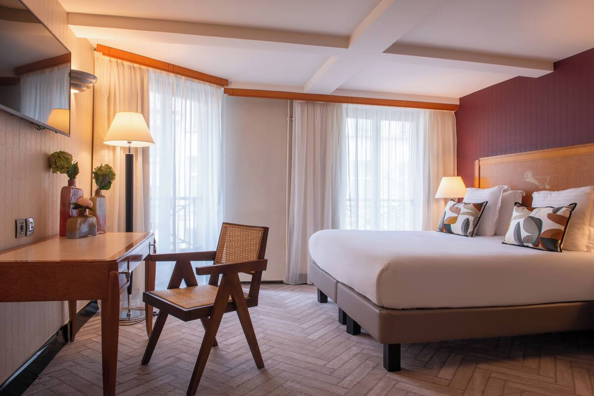 Ein Hotelzimmer mit Bett, Schreibtisch, Stuhl und Lampe.