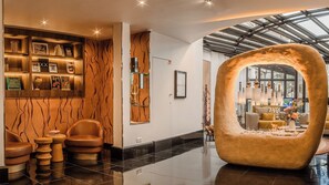 A modern lobby with a curved seating area, a fireplace, and a wall with a unique wavy pattern. - Les Jardins du Marais (Paris)