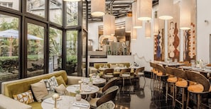 Un restaurante con una decoración moderna, que incluye mesas redondas, asientos acolchados e iluminación colgante.