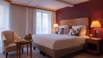A hotel room with a large bed, two bedside tables, a chair, and a small table with a lamp.