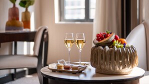Una mesa con un pastel, dos copas de vino blanco y una bandeja de macarons.