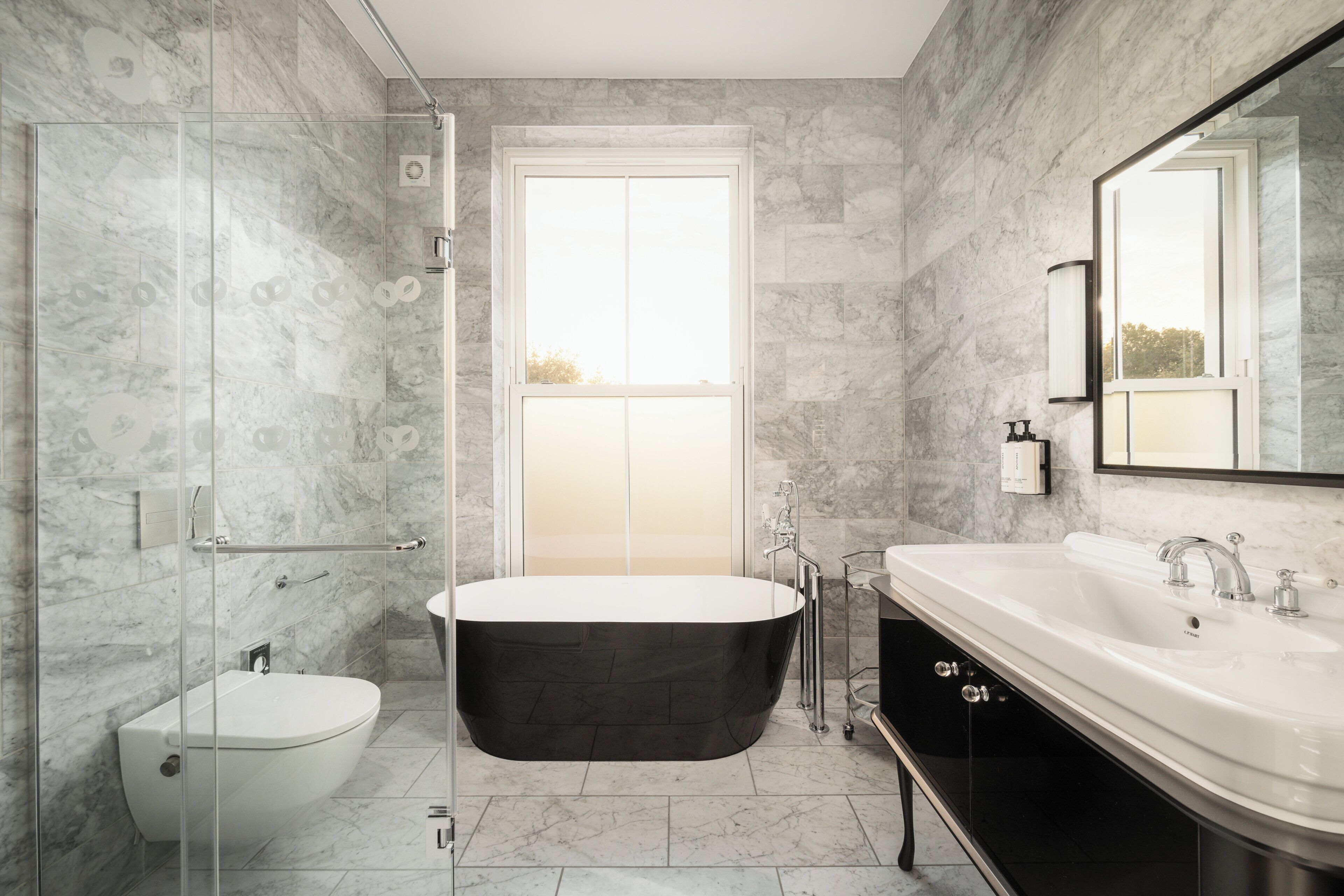 Un baño moderno con una bañera independiente, ducha con cerramiento de vidrio y un espejo grande.