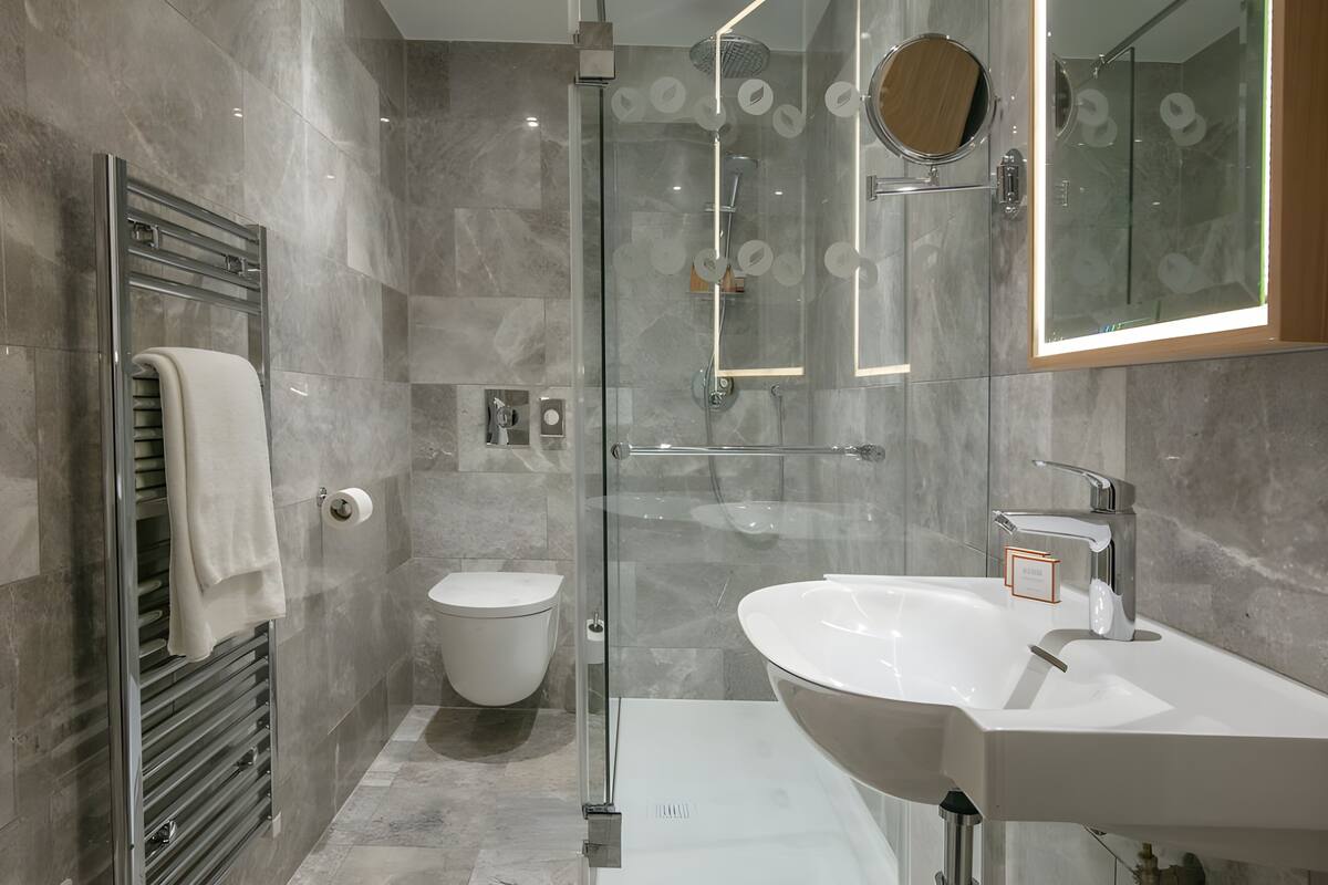 Une salle de bain moderne avec une douche à parois de verre, des toilettes et un grand lavabo avec un miroir.