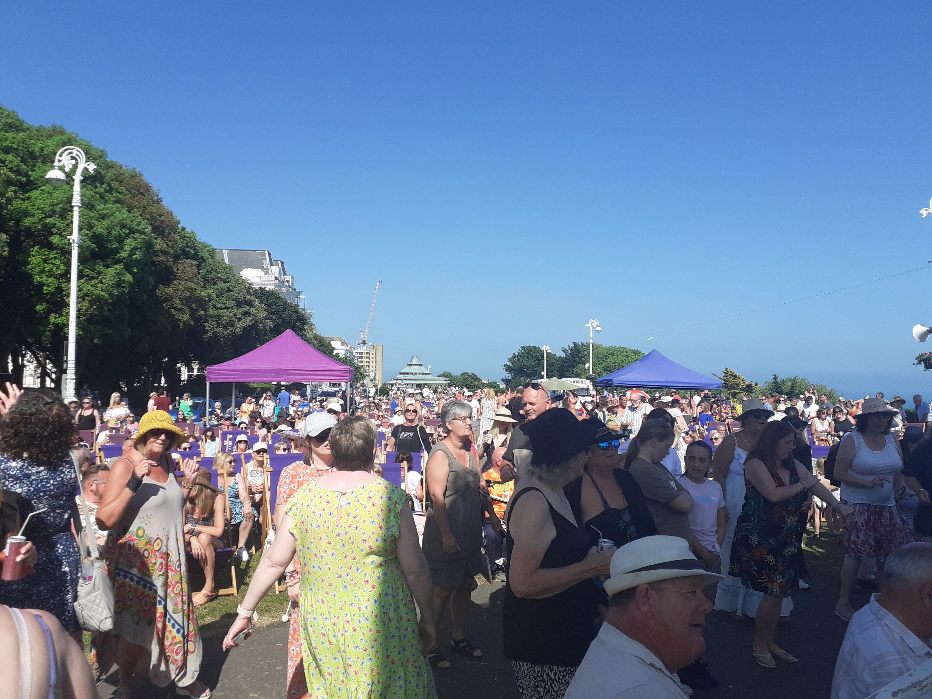A crowded outdoor event with people standing and walking around.