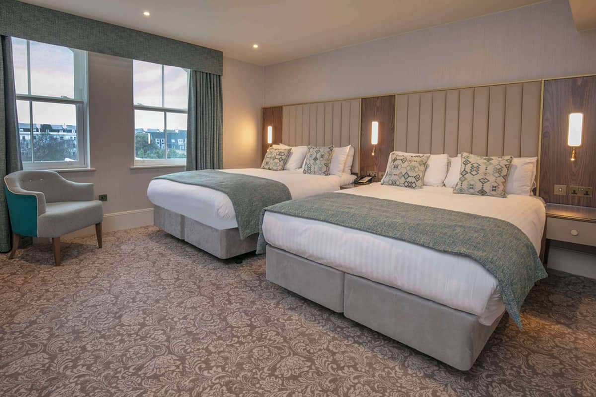 Une chambre d’hôtel avec deux lits, une chaise et de grandes fenêtres.