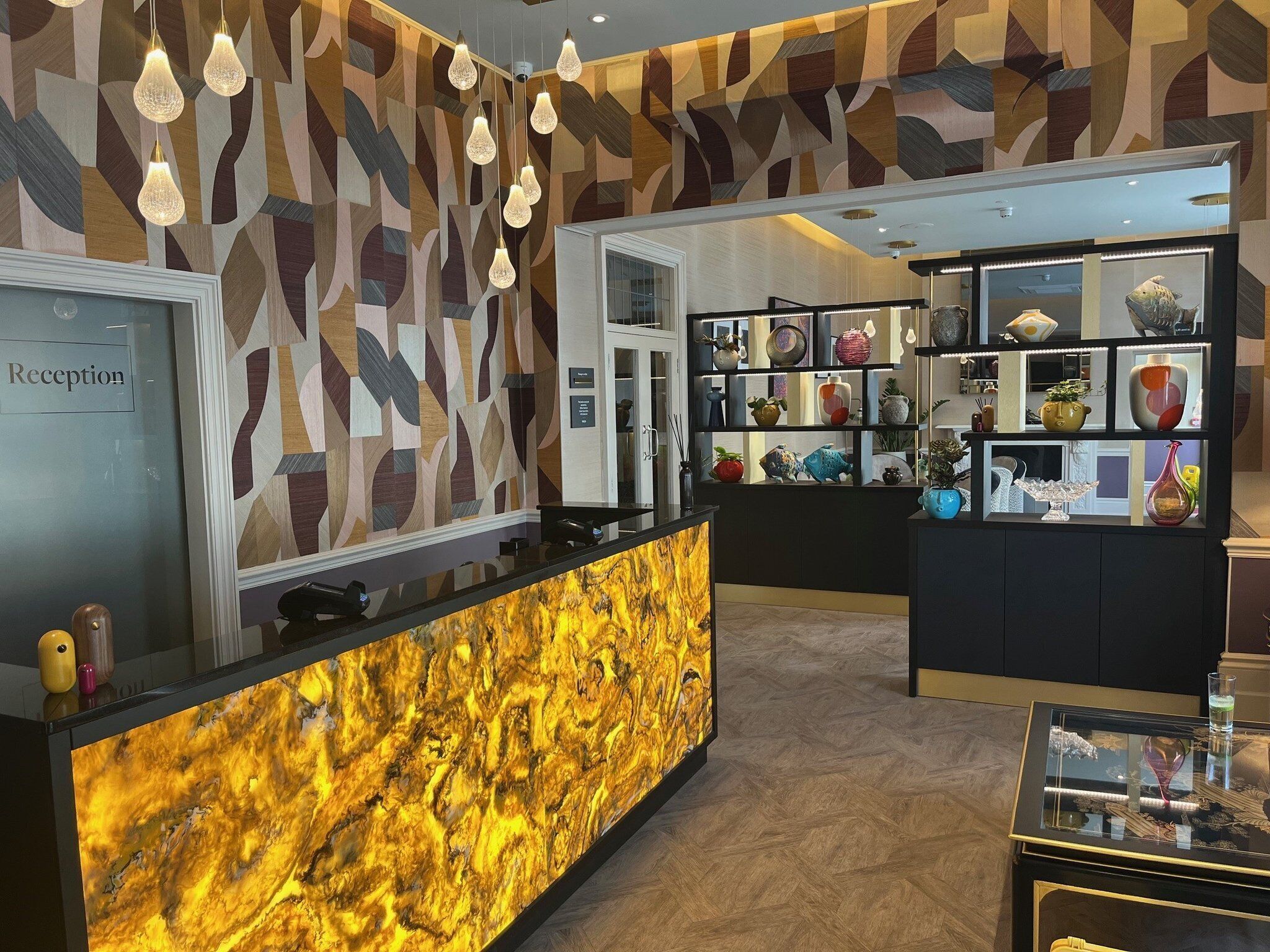 A reception area with a marble counter, geometric patterned walls, and a display of decorative items.