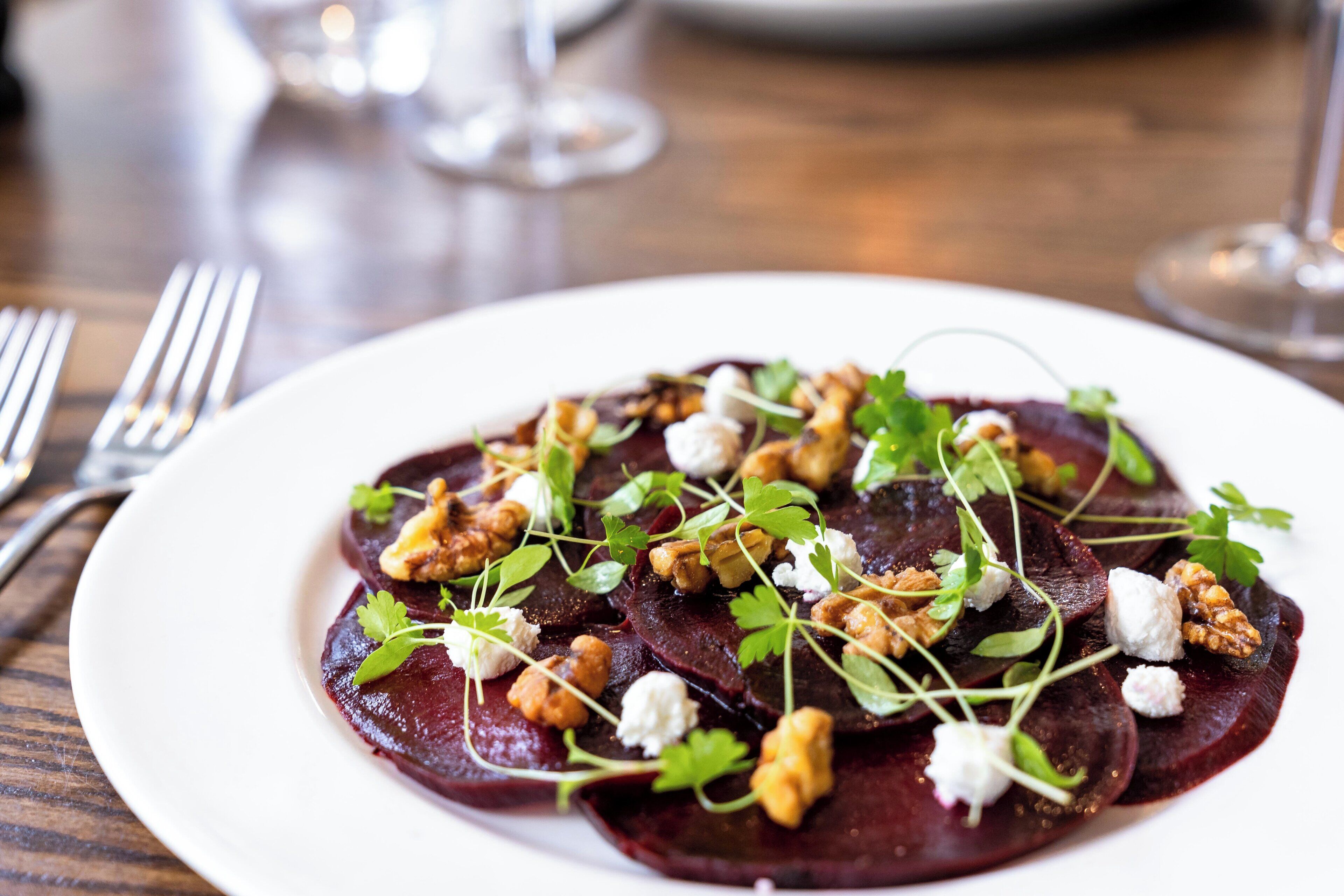 A plate of beetroot salad with walnuts and cheese on a wooden table.