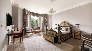 A spacious bedroom with a large bed, a desk, a chair, and a sofa.