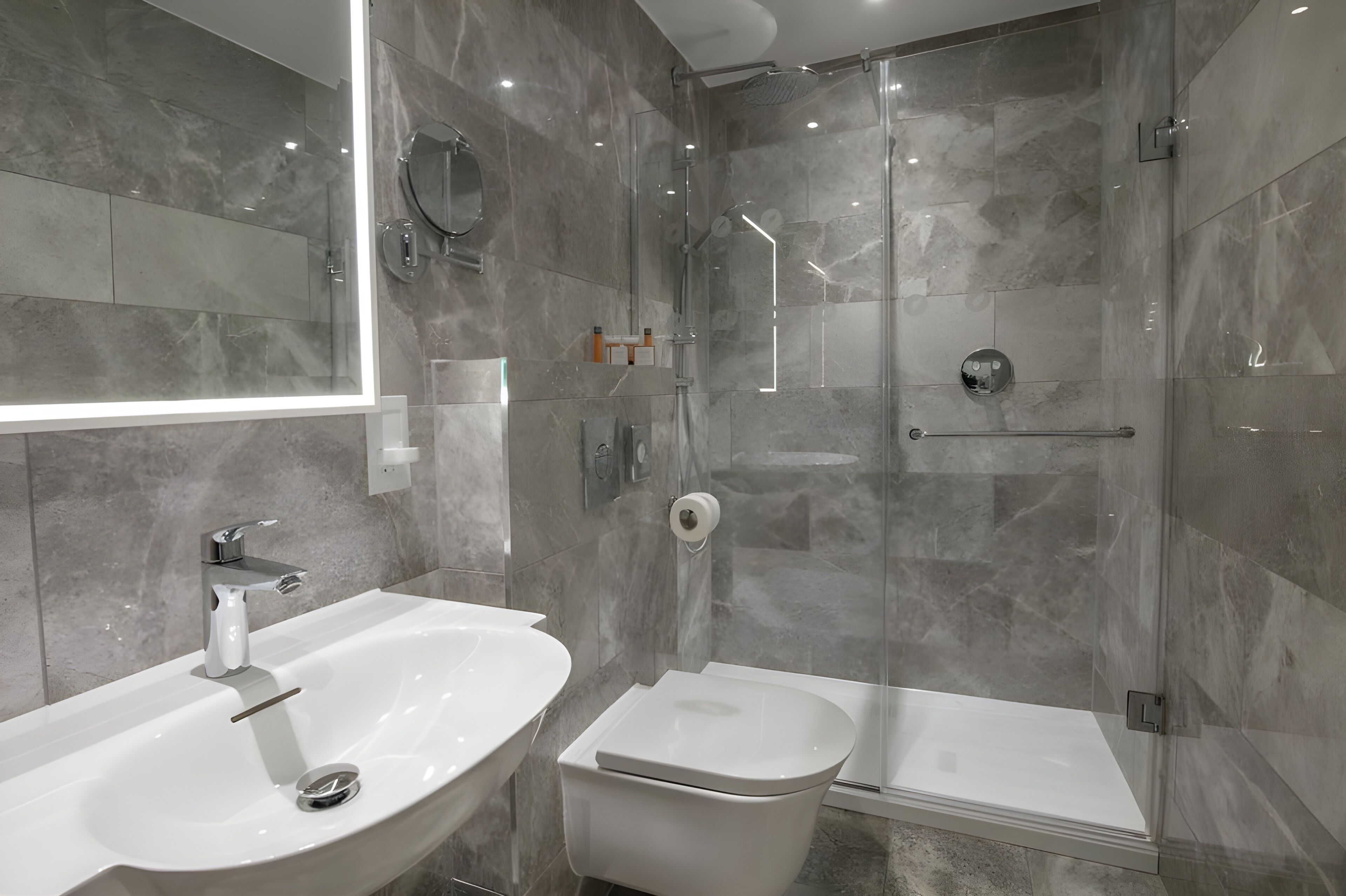 A modern bathroom with a large sink, toilet, and glass-enclosed shower.