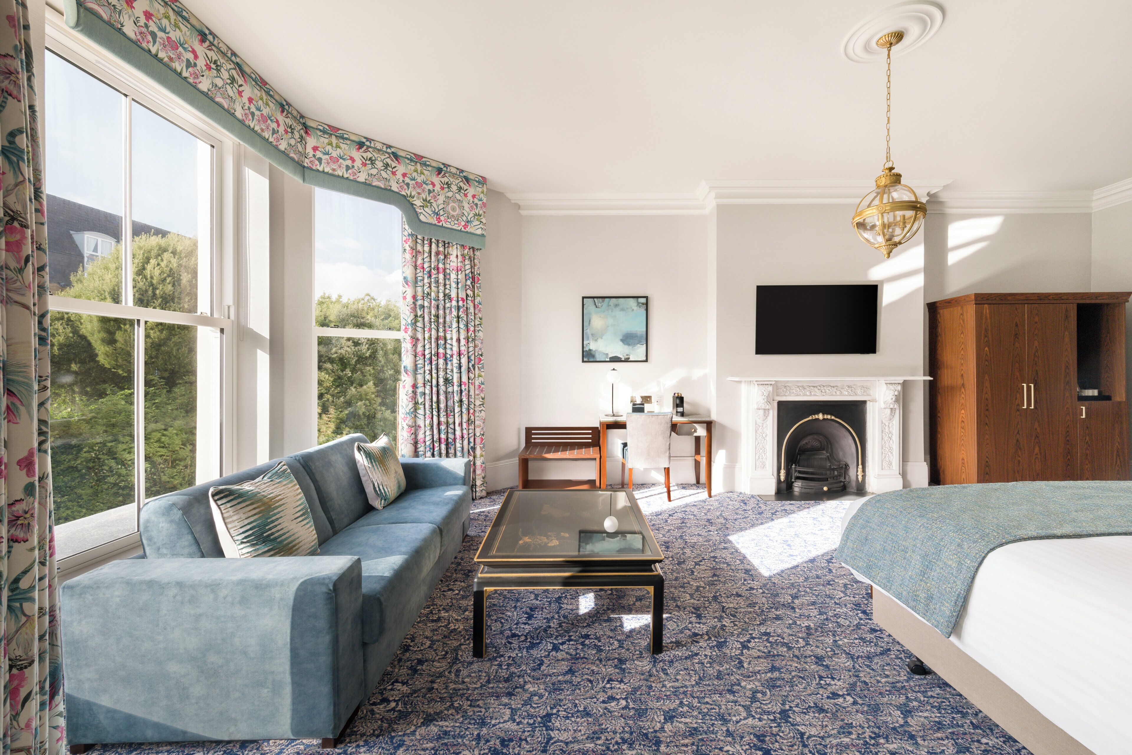 A room with a sofa, a coffee table, a bed, a fireplace, and a television.